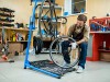 Repair specialist holding bicycle wheel over toolkit while checking it up
